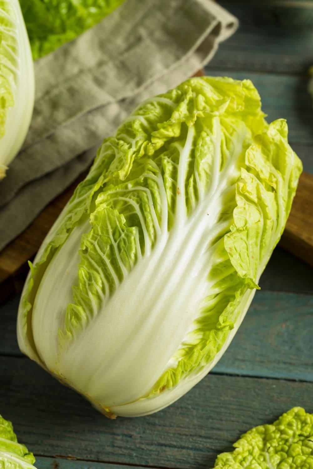 A close-up photo of a head of green cabbage on a wooden cutting board. 