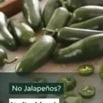 A close-up photo of a cutting board with several jalapenos on it.